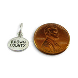 Brocosi.com sterling silver oval Brown County charm next to a penny for scale
