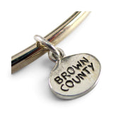 Brocosi.com sterling silver oval Brown County charm with oxidized lettering on a silver bangle bracelet