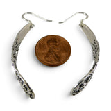 Brocosi.com sterling silver curved dangle earrings with intricate Victorian scrollwork, shown next to a US penny.